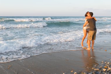 Genç çift gece karanlığında puslu bir sahilde yürüyüş sahiptir.