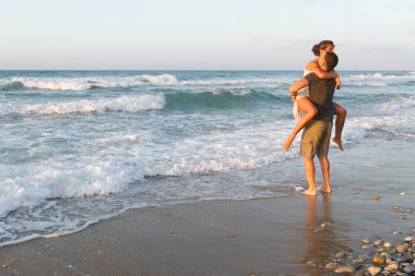 Genç çift gece karanlığında puslu bir sahilde yürüyüş sahiptir.