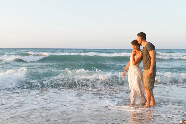 Mladý pár se těší, chůze na mlhavé pláže za soumraku. — Stock fotografie
