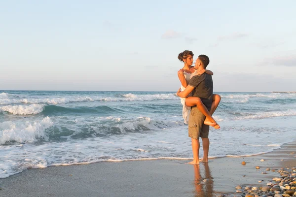 Pareja joven disfruta caminando en una playa nebulosa al atardecer . — Foto de Stock