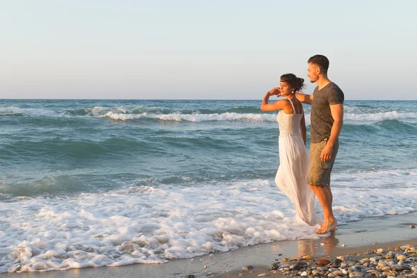 Giovane coppia gode di camminare su una spiaggia nebbiosa al tramonto . — Foto Stock