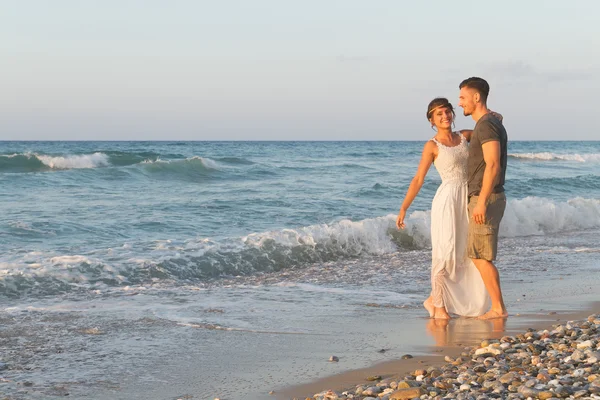 Young couple enjoys walking on a hazy beach at dusk. — Stock Photo, Image