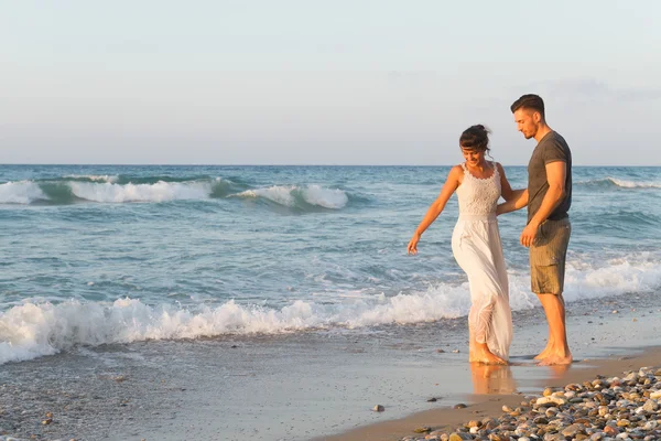 Jeune couple aime marcher sur une plage brumeuse au crépuscule . Image En Vente