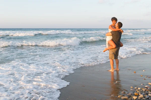 Jeune couple aime marcher sur une plage brumeuse au crépuscule . Images De Stock Libres De Droits