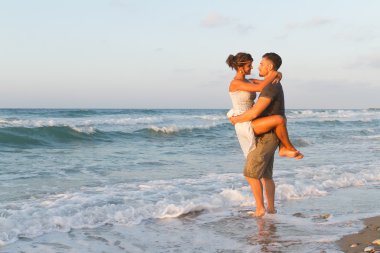 Genç çift gece karanlığında puslu bir sahilde yürüyüş sahiptir.