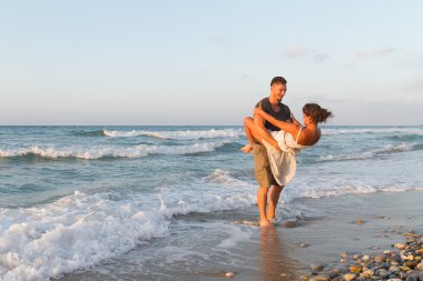 Genç çift gece karanlığında puslu bir sahilde yürüyüş sahiptir.