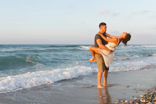 Giovane coppia gode di camminare su una spiaggia nebbiosa al tramonto . — Foto Stock