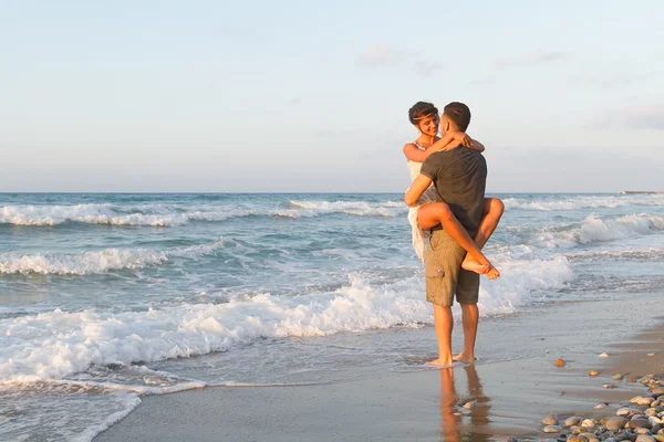 Giovane coppia gode di camminare su una spiaggia nebbiosa al tramonto . — Foto Stock