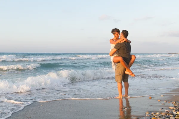 Mladý pár se těší, chůze na mlhavé pláže za soumraku. — Stock fotografie