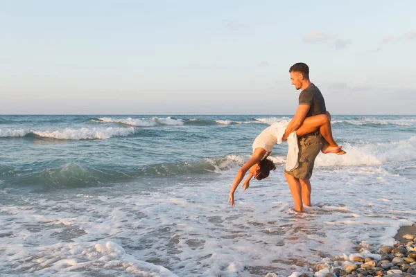 Pareja joven disfruta caminando en una playa nebulosa al atardecer . —  Fotos de Stock