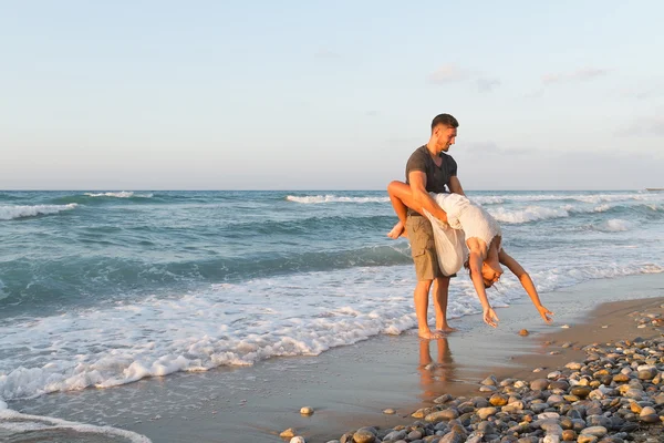 Pareja joven disfruta caminando en una playa nebulosa al atardecer . —  Fotos de Stock