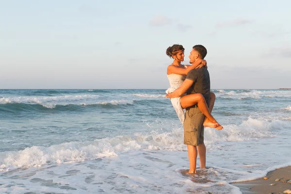 Young couple enjoys walking on a hazy beach at dusk. — Stock Photo, Image