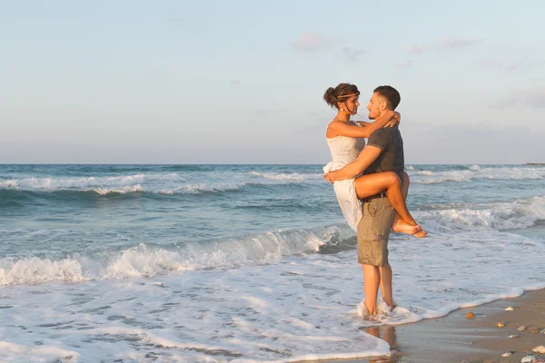 Jovem casal gosta de caminhar em uma praia nebulosa ao entardecer . — Fotografia de Stock