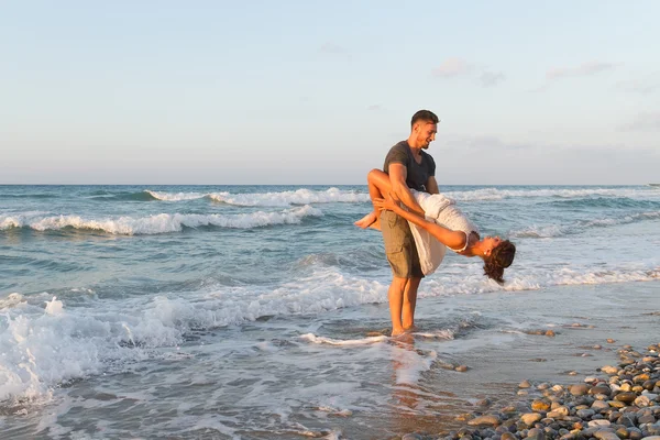 Young couple enjoys walking on a hazy beach at dusk. — Stock Photo, Image