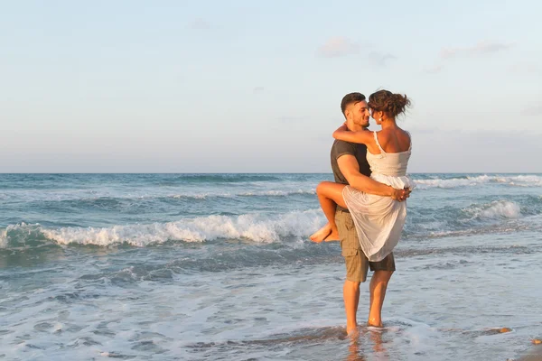 Jeune couple aime marcher sur une plage brumeuse au crépuscule . Image En Vente
