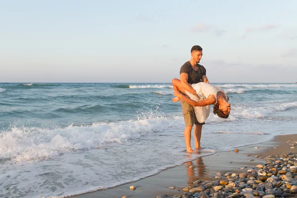 Jeune couple aime marcher sur une plage brumeuse au crépuscule . Images De Stock Libres De Droits