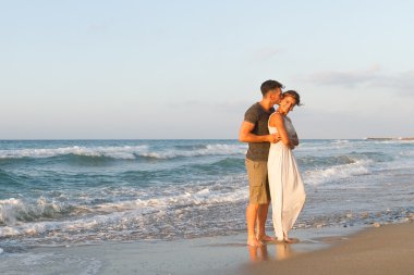 Genç çift gece karanlığında puslu bir sahilde yürüyüş sahiptir.