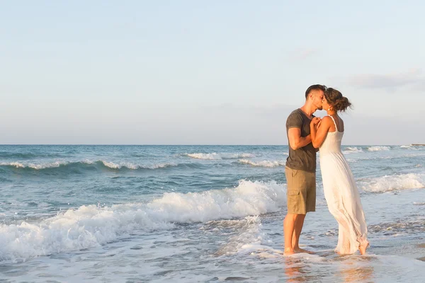 Jovem casal gosta de caminhar em uma praia nebulosa ao entardecer . — Fotografia de Stock