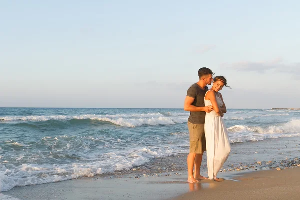 Giovane coppia gode di camminare su una spiaggia nebbiosa al tramonto . — Foto Stock