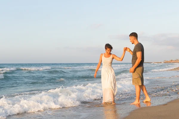 对年轻的夫妇喜欢在黄昏时在朦胧的海滩上散步. — 图库照片