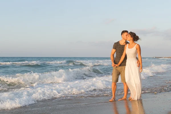 Giovane coppia gode di camminare su una spiaggia nebbiosa al tramonto . — Foto Stock