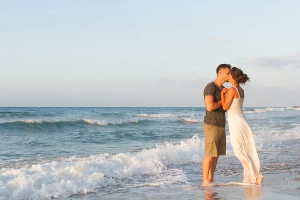 Young couple enjoys walking on a hazy beach at dusk. — Stock Photo, Image