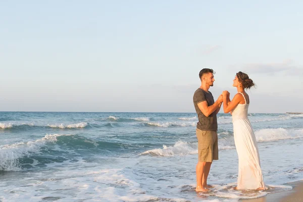 Giovane coppia gode di camminare su una spiaggia nebbiosa al tramonto . — Foto Stock