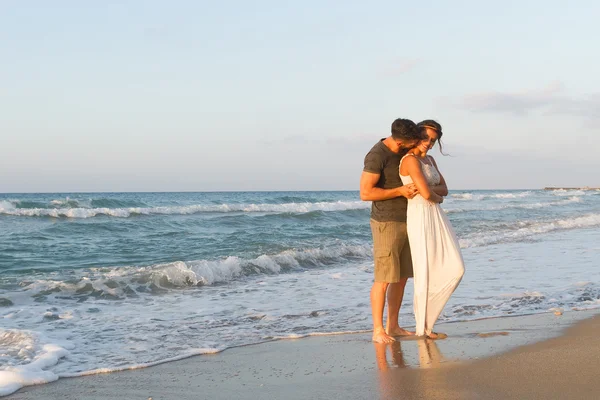 Giovane coppia gode di camminare su una spiaggia nebbiosa al tramonto . — Foto Stock