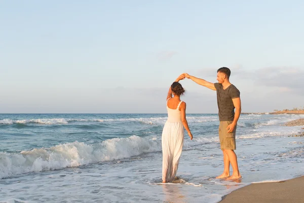 Giovane coppia gode di camminare su una spiaggia nebbiosa al tramonto . — Foto Stock