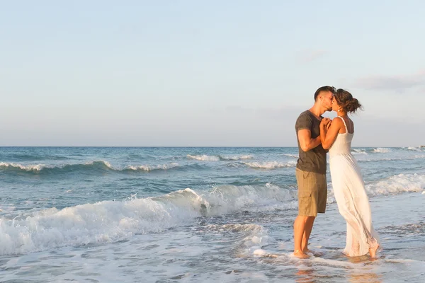 Pareja joven disfruta caminando en una playa nebulosa al atardecer . —  Fotos de Stock