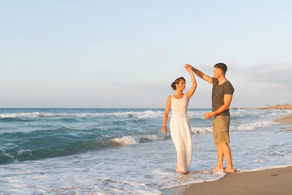 Giovane coppia gode di camminare su una spiaggia nebbiosa al tramonto . — Foto Stock