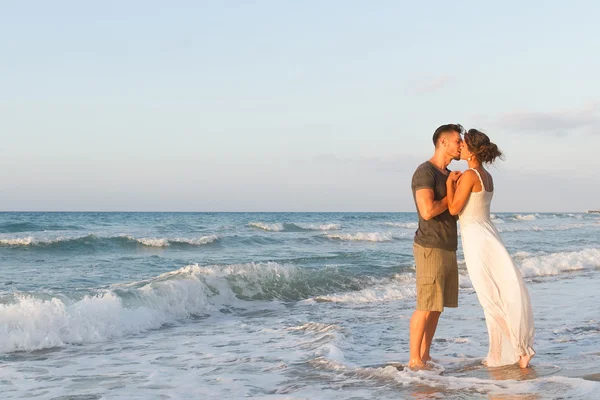 Giovane coppia gode di camminare su una spiaggia nebbiosa al tramonto . — Foto Stock