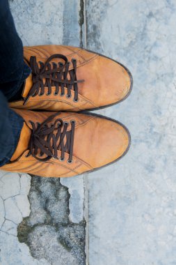 kahverengi deri ayakkabı giyen erkek ayakları