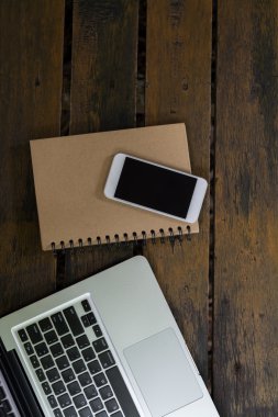 ahşap arka plan üzerinde dizüstü smartphone ve not defteri