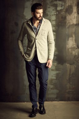 Yakışıklı delikanlı buket çiçek ile akıllı ceketli duvarın önünde poz veriyor.