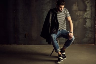 Yakışıklı delikanlı buket çiçek ile akıllı ceketli duvarın önünde poz veriyor.