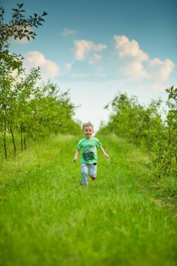 Mutlu küçük çocuk yeşil bahçesinde çalışır 