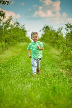 Mutlu küçük çocuk yeşil bahçesinde çalışır 