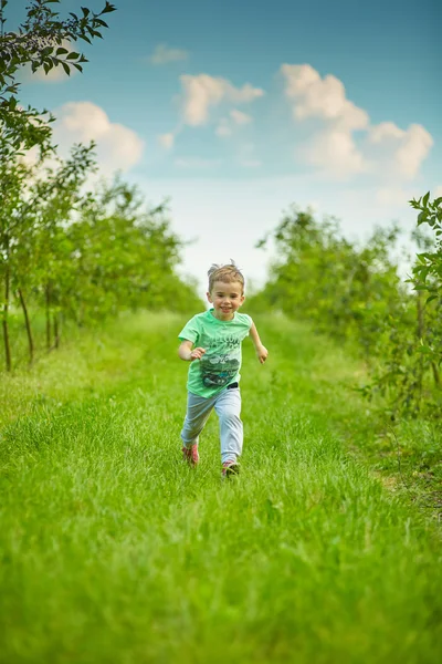 Felice bambino corre nel giardino verde — Foto Stock