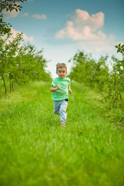 Šťastný chlapec běží v zelené zahradě — Stock fotografie