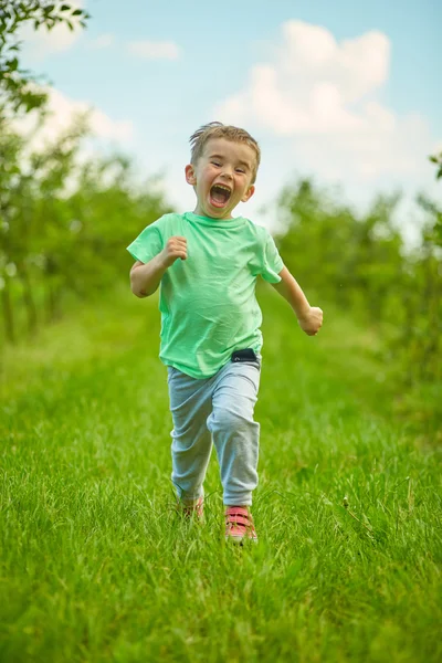 Happy little boy runs in the green garden — Stock Photo, Image