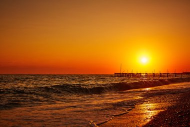 İskele ve deniz dalgaları ile çarpıcı günbatımı