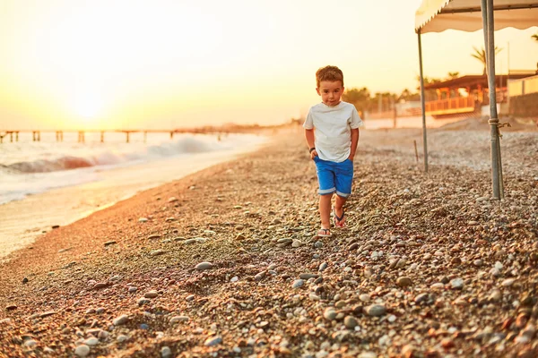 Menino caminhando ao longo da praia ensolarada — Fotografia de Stock