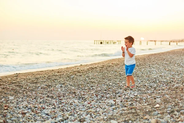 Menino caminhando ao longo da praia ensolarada — Fotografia de Stock