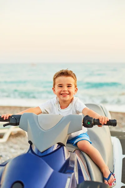 Menino sentado em moto na praia ensolarada — Fotografia de Stock