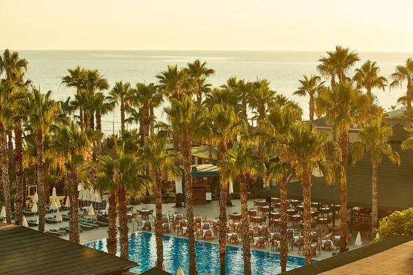 Beautiful sunrise on sea resort with palms and swimming pool