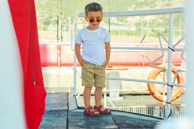 Komik küçük çocuk güzel dağlar yakınındaki gezi teknesinde poz