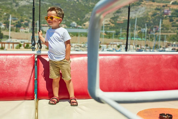 Engraçado menino posando em barco de excursão perto de belas montanhas — Fotografia de Stock