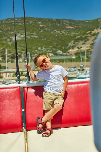 Engraçado menino posando em barco de excursão perto de belas montanhas — Fotografia de Stock