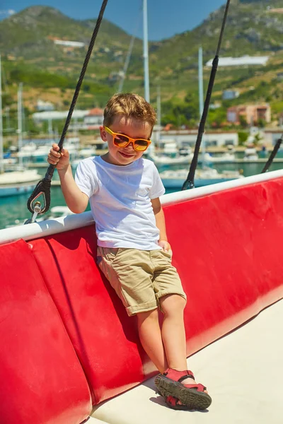 Engraçado menino posando em barco de excursão perto de belas montanhas — Fotografia de Stock